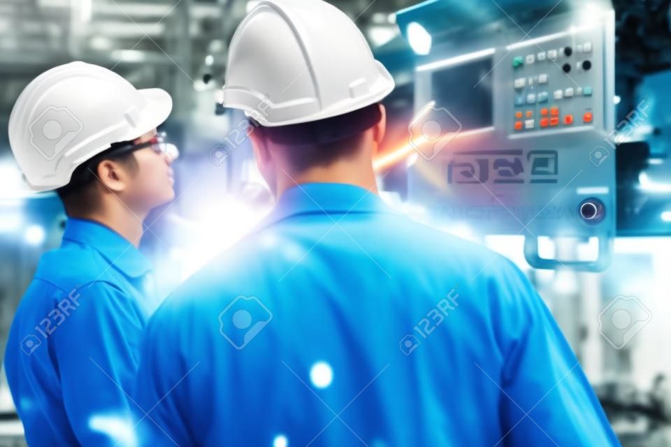Gruppo di abili operai di fabbrica che utilizzano attrezzature per macchine in officina. Concetto di tecnologia per persone dell'industria e dell'ingegneria.
