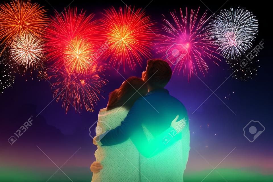 Glückliches junges Paar umarmt, während ein Feuerwerk den Himmel färbt. herrliche generative KI.