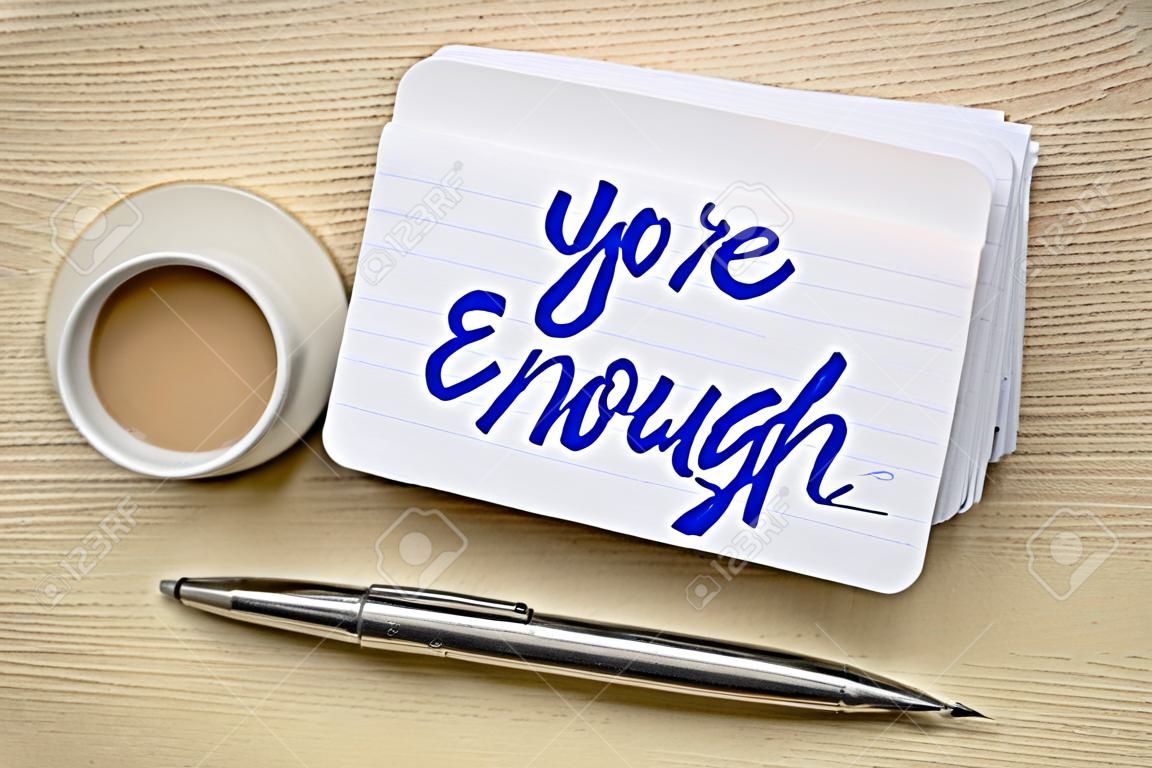 you are enough concept - handwriting on a stack of index cards with a cup of coffee and a pen against textured bark paper