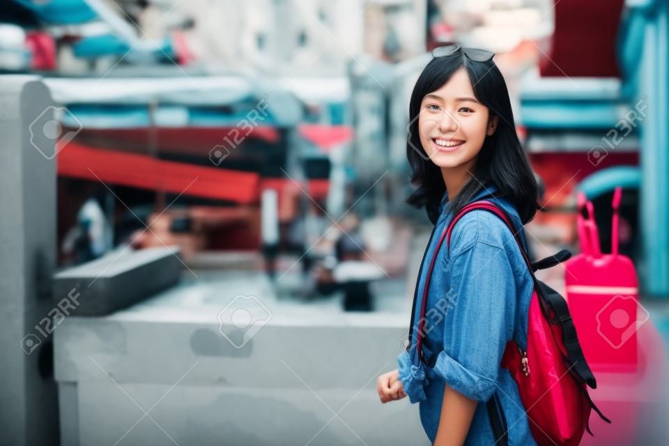 地元の場所と笑顔を楽しむアジアの若い女性のバックパック旅行者。