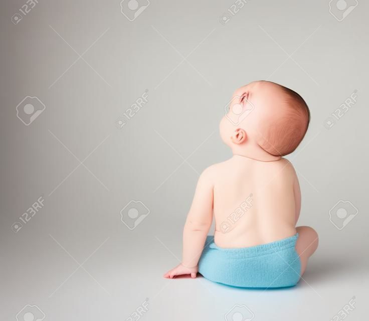 Baby toddler sitting facing backwards isolated on a white background