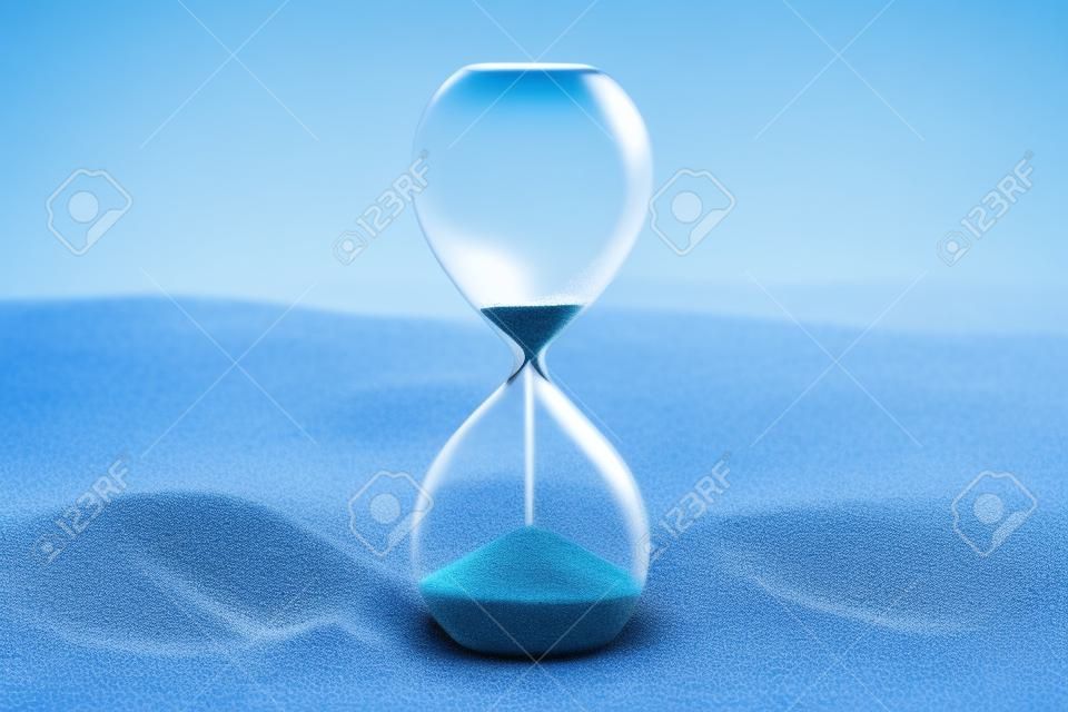 De tijd raakt op. Een zandloper met zand dat er doorheen valt, op een levendige blauwe achtergrond met een plek voor tekst