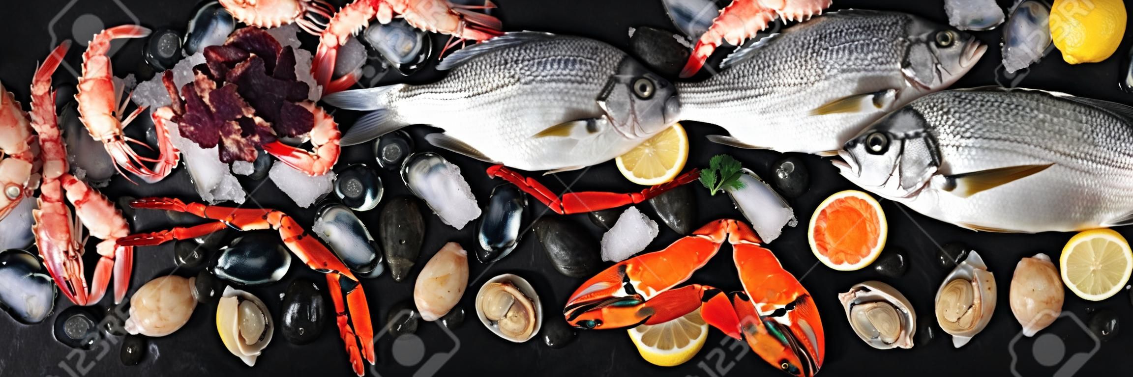 Panorama ryb i owoców morza, płaskie ujęcie z góry. Dorada. krewetki, kraby, sardynki, kalmary, ośmiornice i przegrzebki na lodzie z cytryną i kawiorem