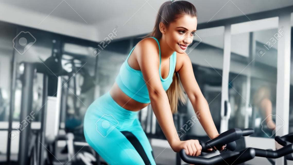 Young beautiful girl on an exercise bike in a gym