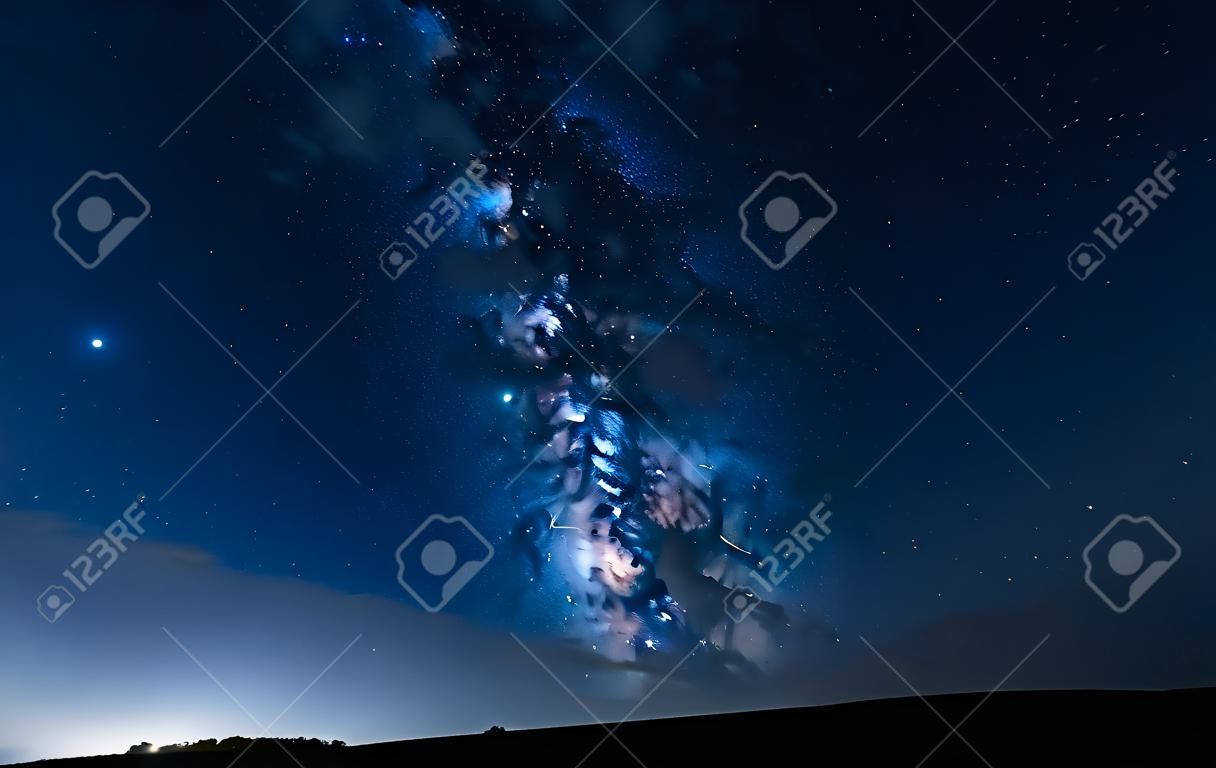 Milchstraße einen Hügel hinauf in einem sternenklaren Nachthimmel. Blauer Himmel mit Sternen ohne Lichtverschmutzung.