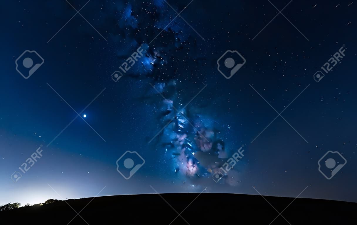 Milchstraße einen Hügel hinauf in einem sternenklaren Nachthimmel. Blauer Himmel mit Sternen ohne Lichtverschmutzung.