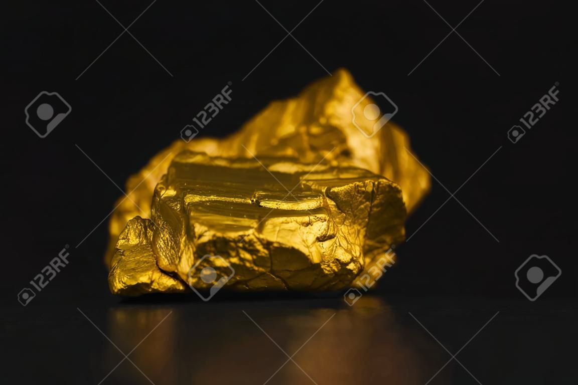 Closeup of gold nugget or gold ore on black background, precious stone or lump of golden stone, financial and business concept idea.