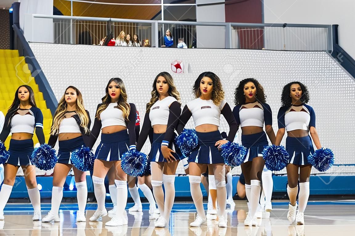 A group of cheerleaders in mini-skirts and knee-highs holding pom-poms showing team spirit.