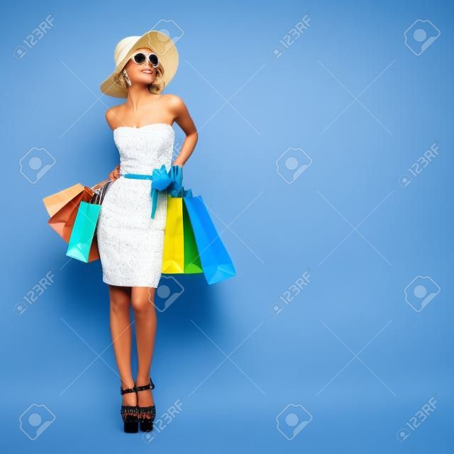 購物風格。藍色背景上迷人的女士拿著袋子