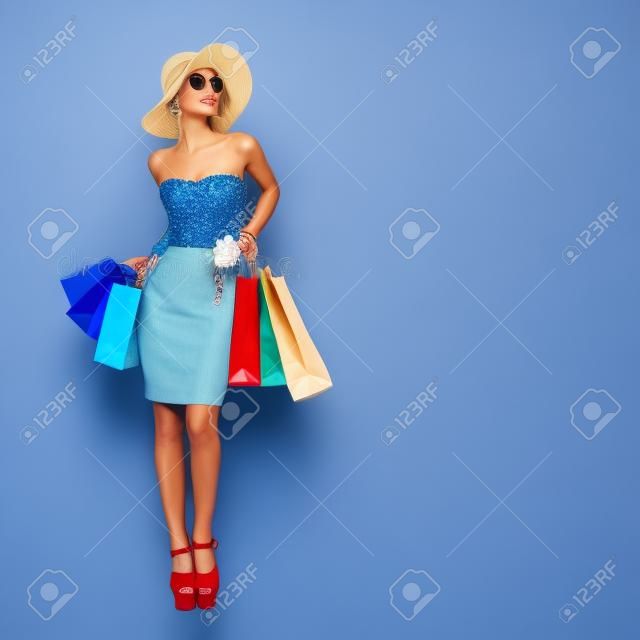 購物風格。藍色背景上迷人的女士拿著袋子