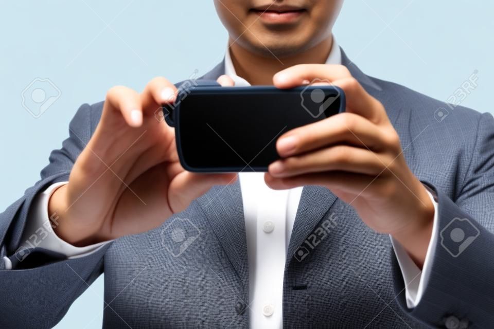Hombre de negocios asiático con una cámara móvil en el fondo blanco