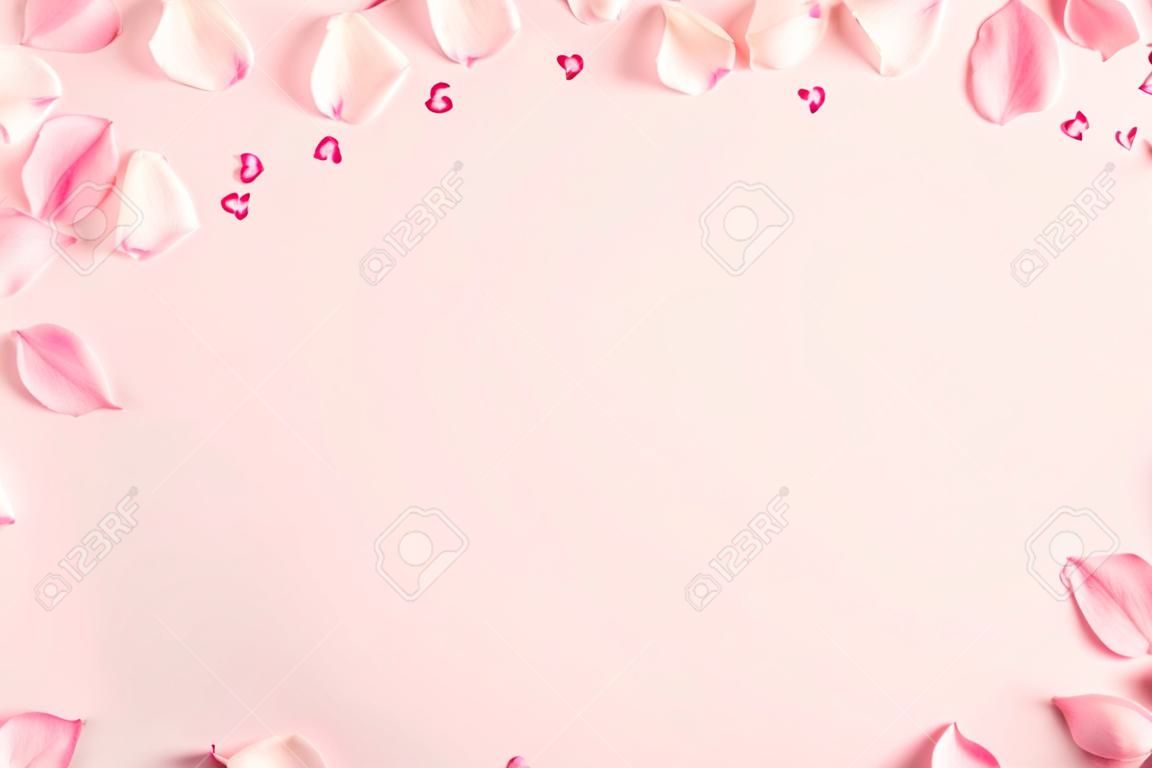 Composizione di fiori. Petali di fiori di rosa su sfondo rosa pastello. San Valentino, festa della mamma, concetto di festa della donna. Disposizione piana, vista dall'alto, copia spazio