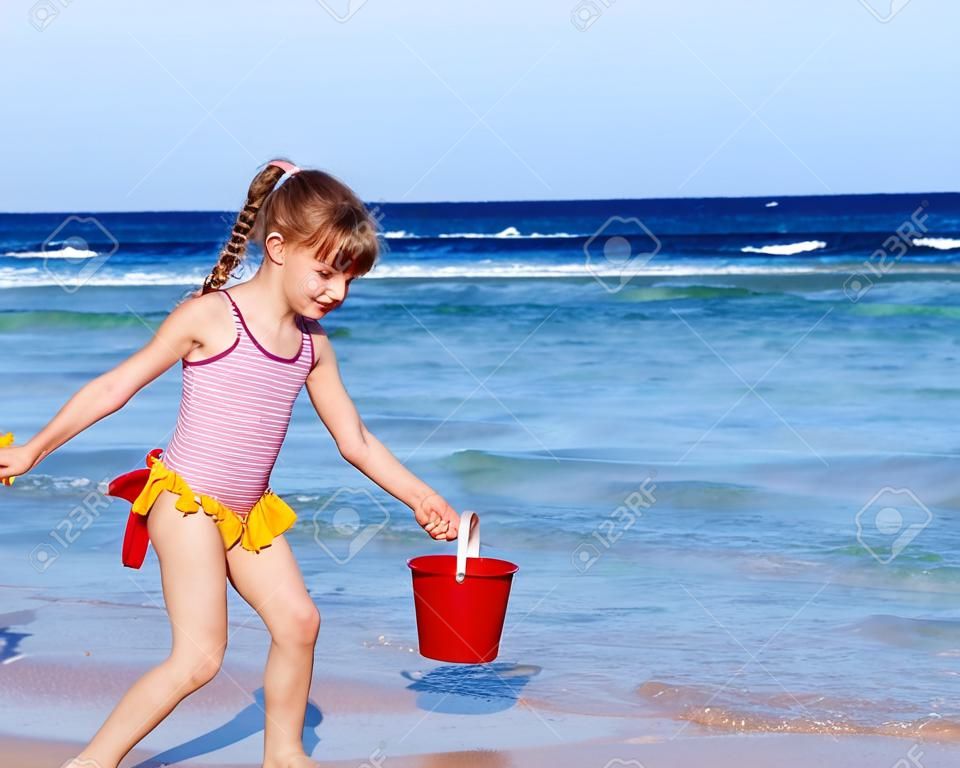 Две маленькие девочки играют на пляже с ведерками и совочками
