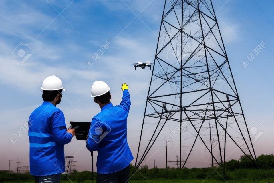 엔지니어 위치의 팀 작업은 기술자가 드론을 사용하여 발전소에서 검사를 비행하여 전기 고압 송전탑을 생산하여 계획 작업을 볼 수 있도록 도와줍니다.