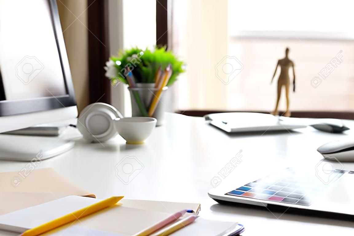 Vista lateral Lugar de trabajo de oficina moderno con tableta digital, bloc de notas, lápices de colores, computadora por la mañana.