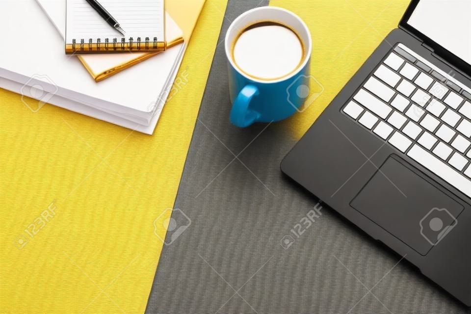 Stylish workplace with computer laptop, coffee cup and notepad on colorful background. Top view.