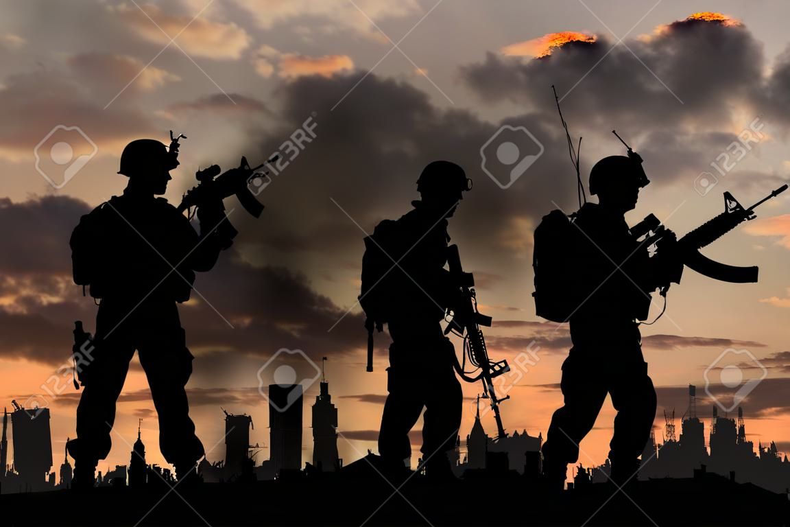 concept of war. Silhouettes of military soldiers with weapons against the backdrop of the city in the smoke and explosions