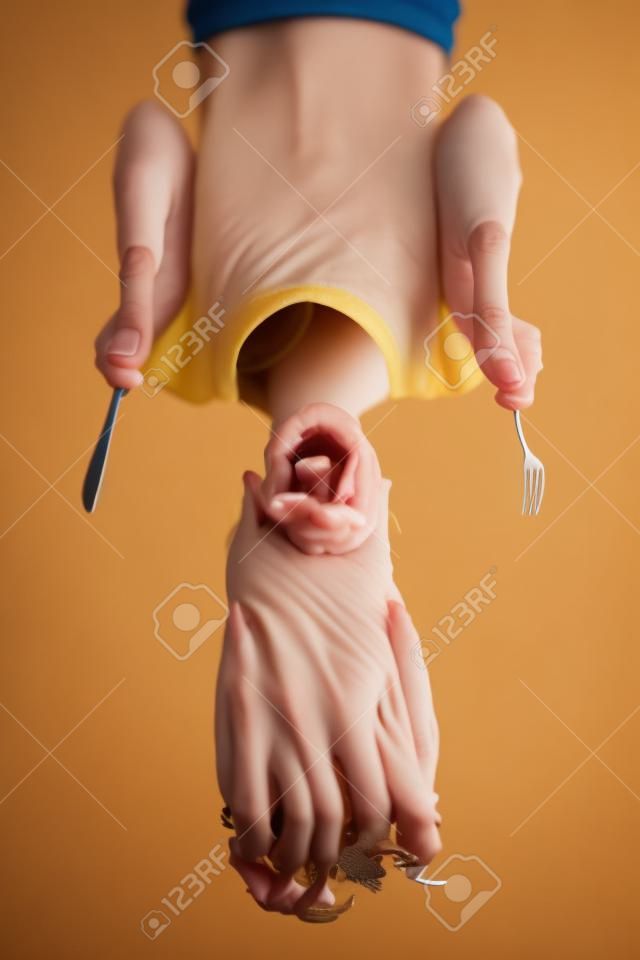 Excited young woman holding a fork and a knife being ready to have dinner