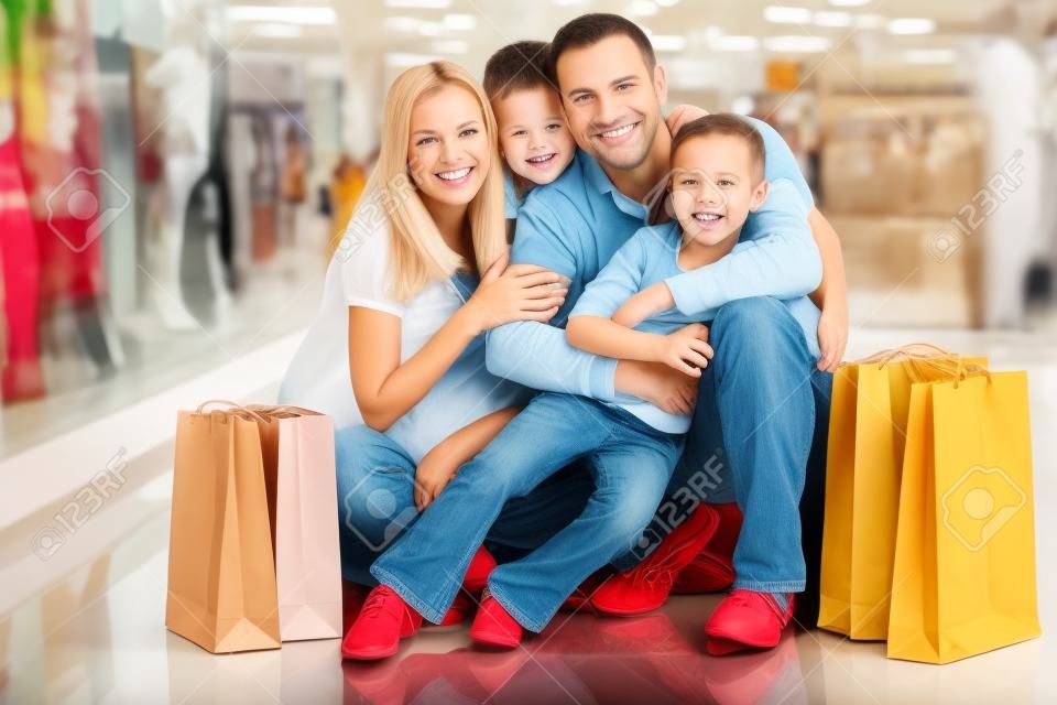 Portrait of joyful family with paperbags looking at camera in the mall
