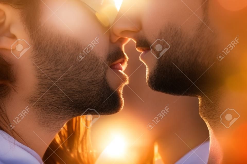 Close-up of young people kissing against the sun