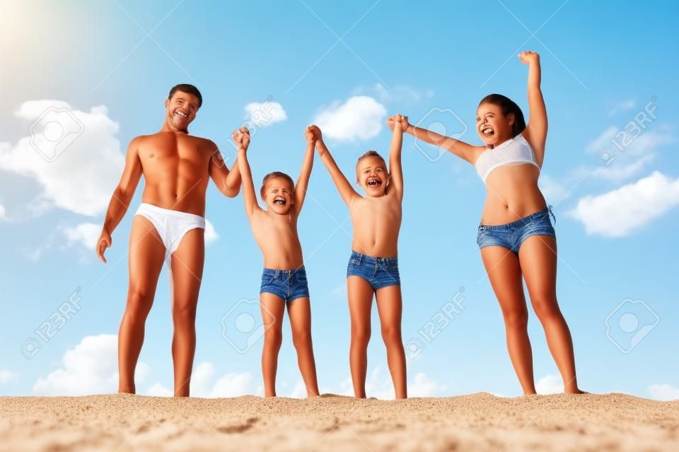 Foto de familia feliz de pie en la arena durante las vacaciones de verano