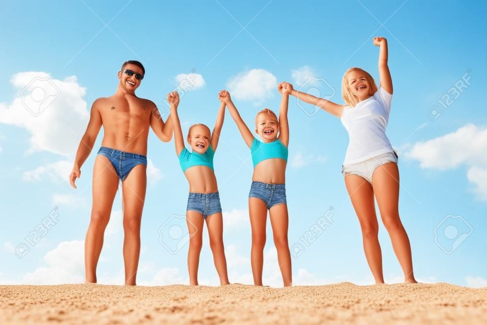 Foto de familia feliz de pie en la arena durante las vacaciones de verano