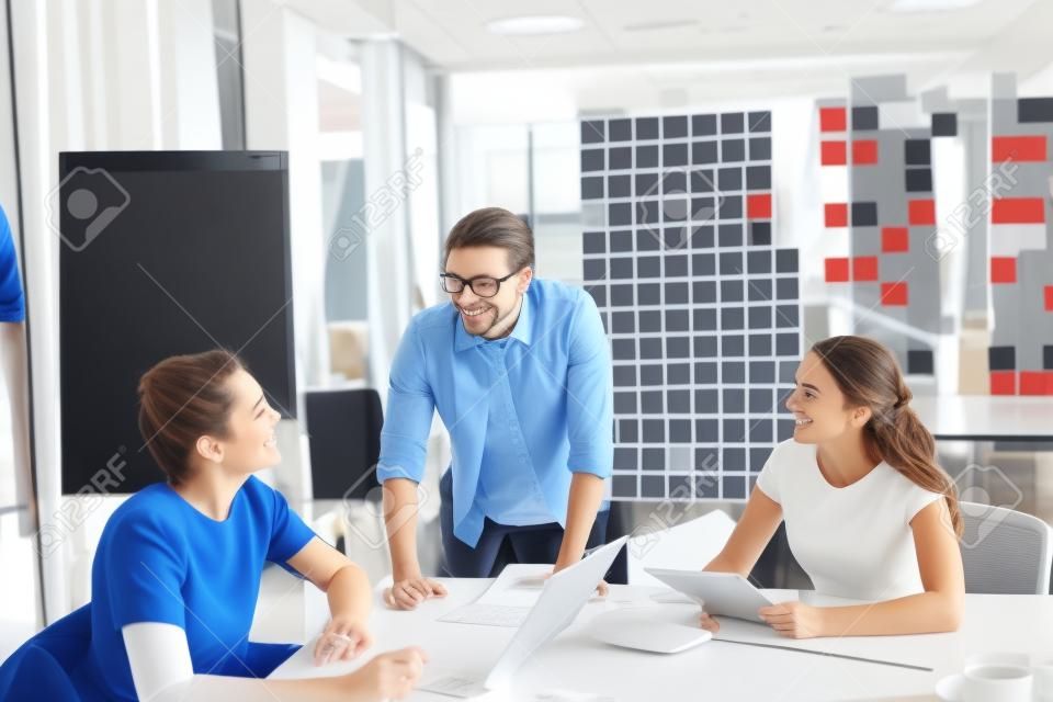 Group of three successful business partners in casual communicating at meeting in office