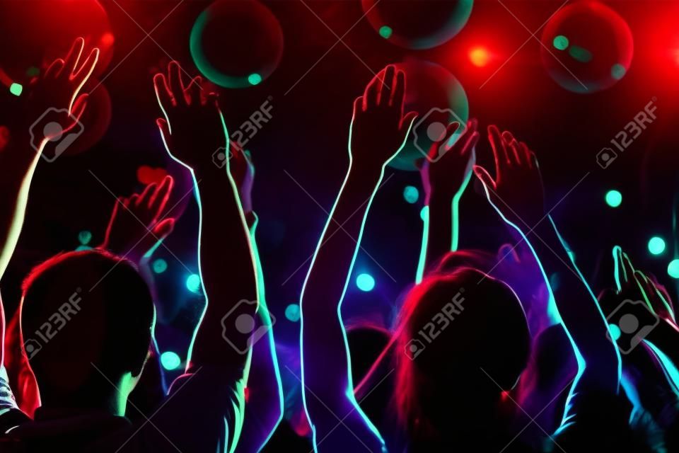 Arms of friends dancing in night club