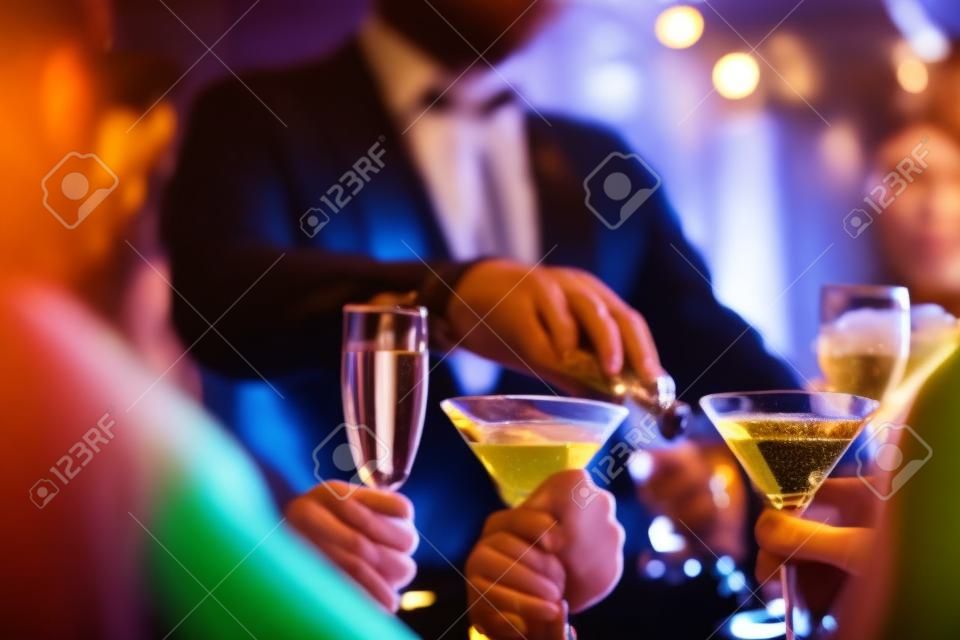 Mains de jeunes titulaires martini et champagne dans le bar