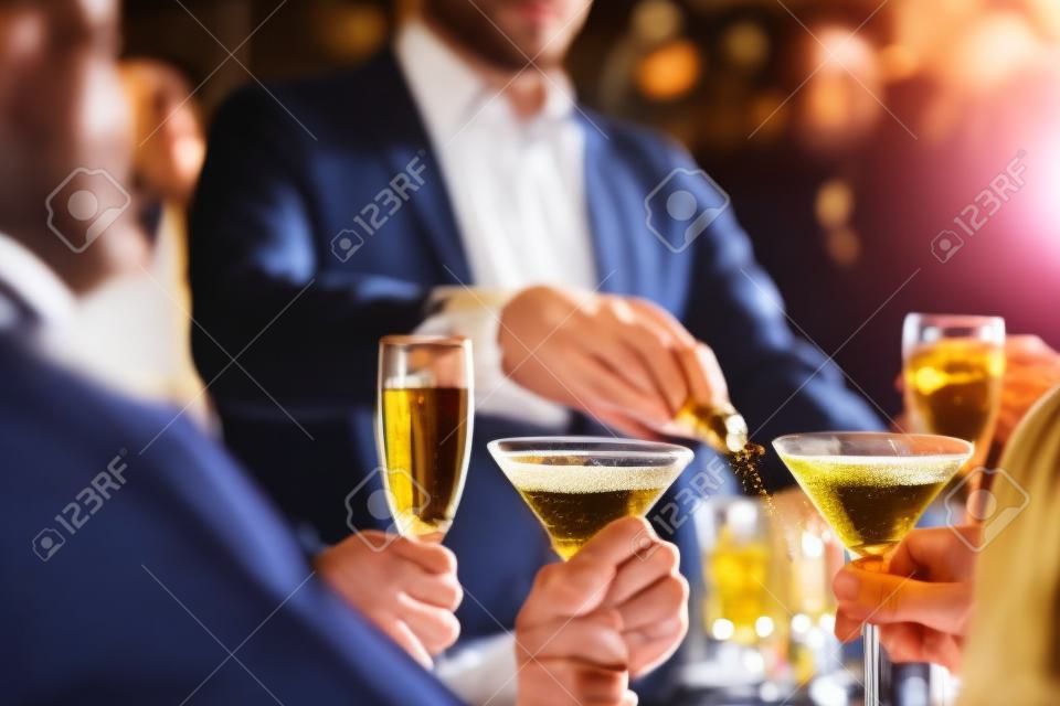 Mains de jeunes titulaires martini et champagne dans le bar