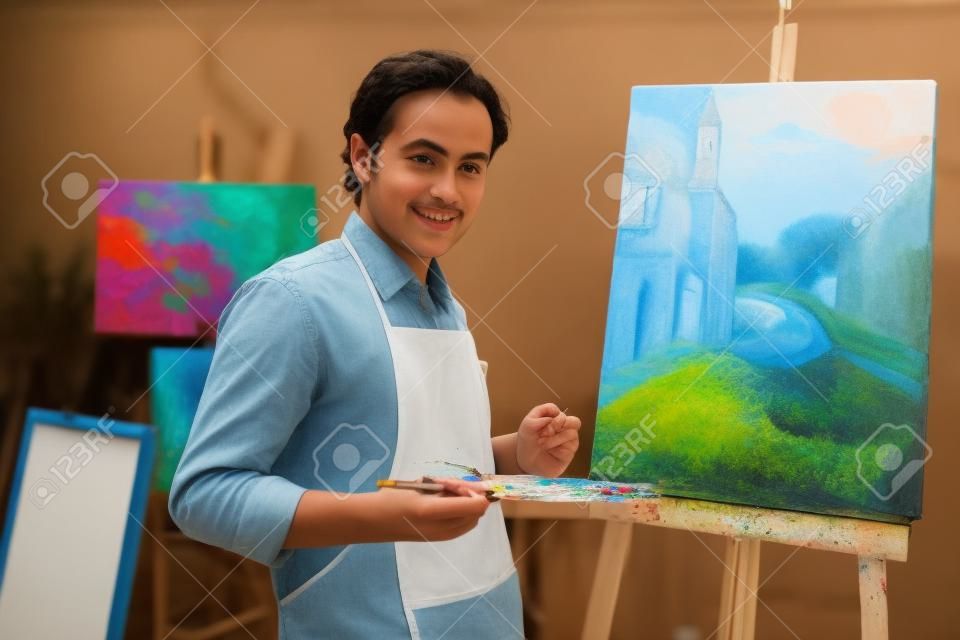 年輕的藝術家在他的繪畫的背景看，照相機