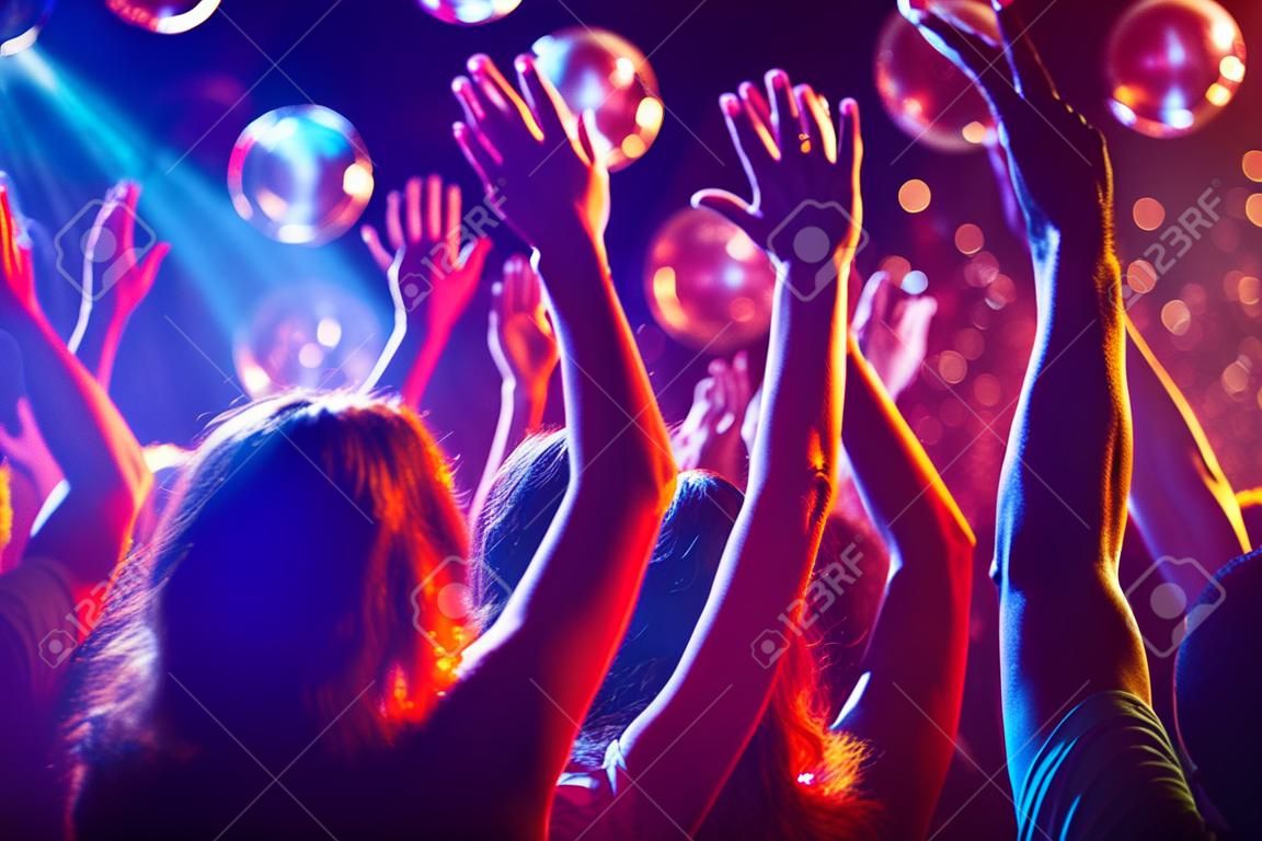 Menge von Menschen mit erhobenen Armen tanzen in Nachtclub