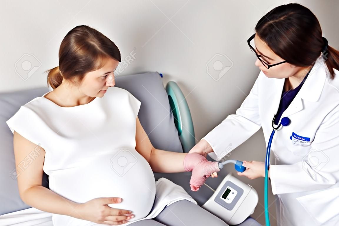 Médico medindo a pressão da mulher grávida no hospital