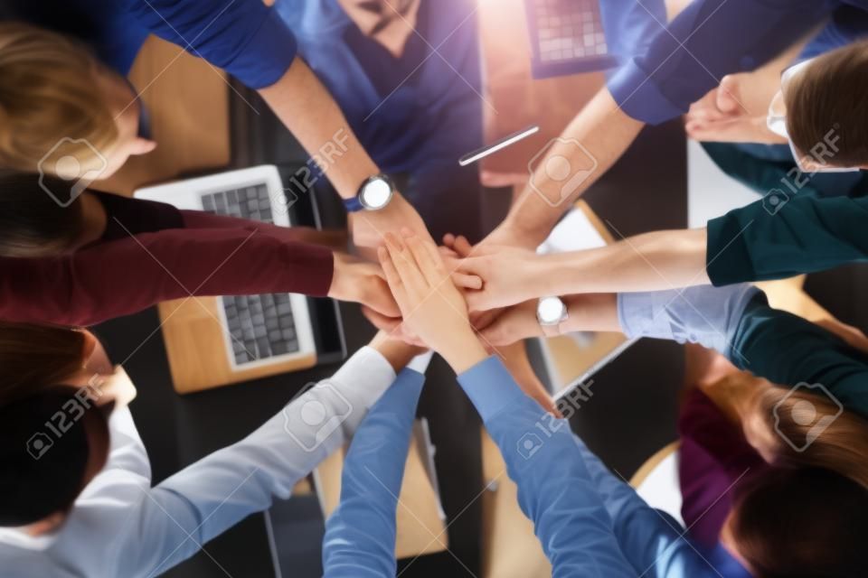 Heap of hands of co-workers over table