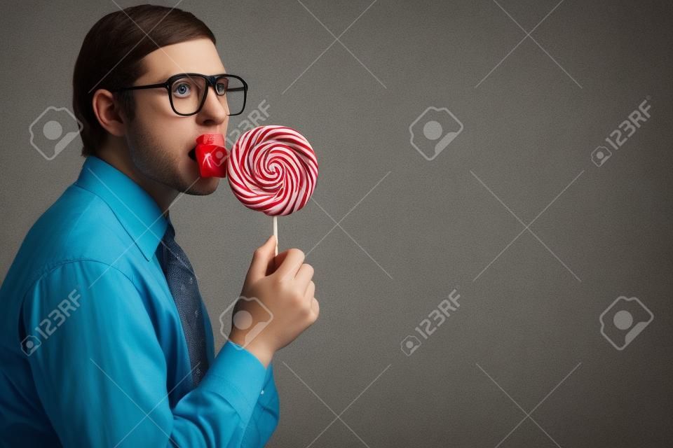 Portrait of nerd boy sucking a lollipop and looking at camera in suspense