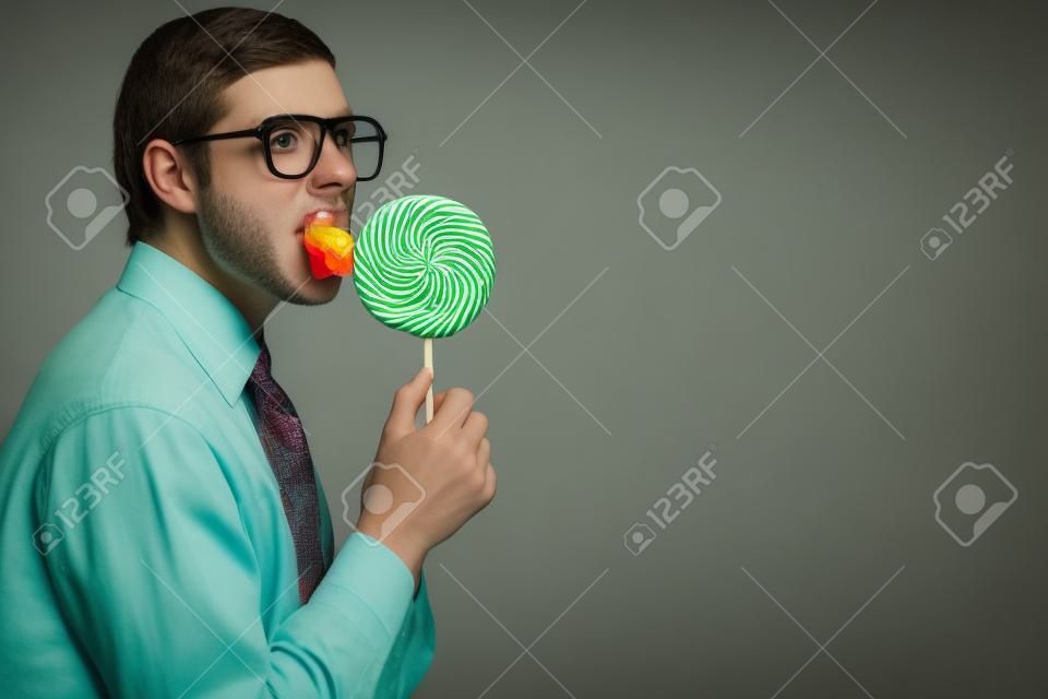 Portrait of nerd boy sucking a lollipop and looking at camera in suspense