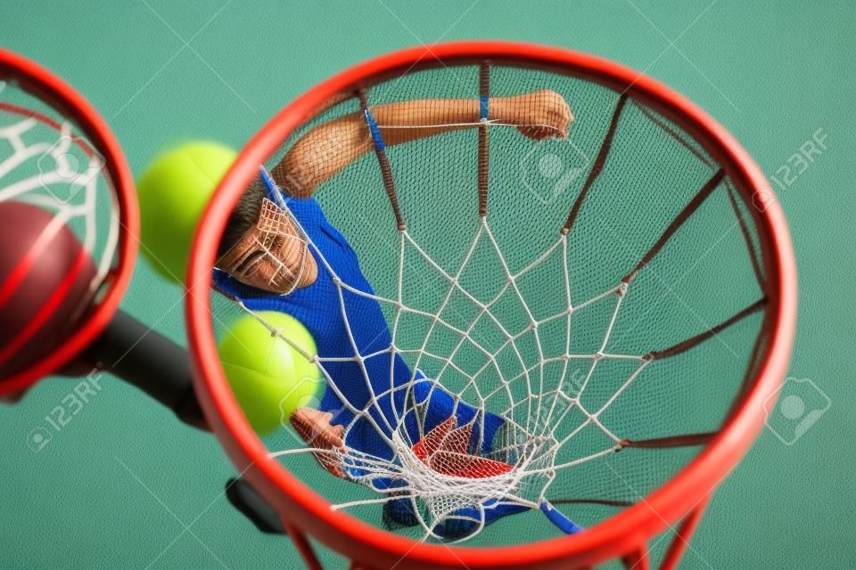 Vista da cesta com rede e bola de arremesso de jogador jovem abaixo