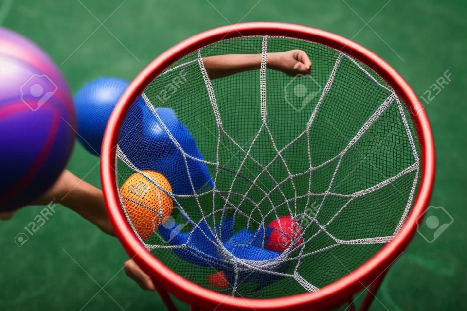 Vista da cesta com rede e bola de arremesso de jogador jovem abaixo