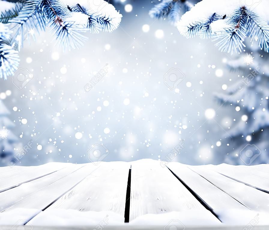 보케 조명, 눈송이, 빈 오래된 나무 테이블이 있는 겨울 장식 크리스마스 배경. 눈송이와 크리스마스와 새 해 복 많이 받으세요 파란색 배경입니다. 떨어지는 눈과 전나무 나뭇가지가 있는 겨울 풍경.