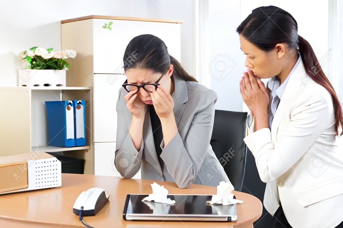 грустная депрессия бизнес-леди, получающая сообщение об увольнении, плачет в рабочем офисе и довольно элегантная девушка-коллега по компании утешает ее.