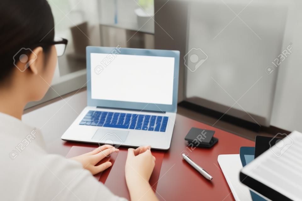 вид сзади студентки университета, использующей мобильный ноутбук, обучающейся через систему электронного обучения онлайн с белым пустым экраном. селективный фокус фото.