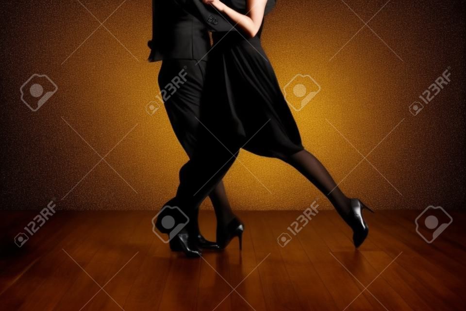 Junge hübsche Frau im schwarzen Kleid und Mann tanzen Tango
