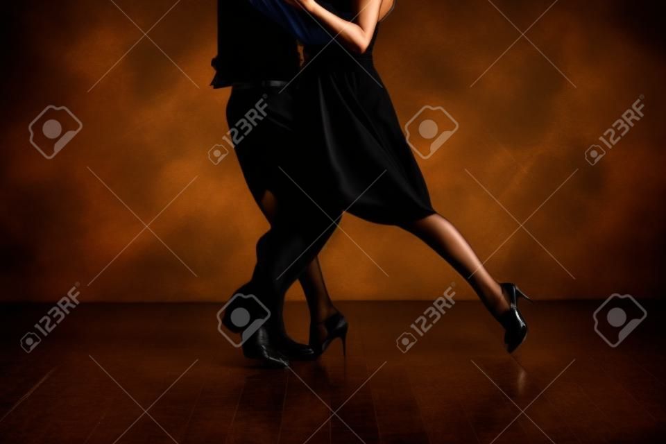 Junge hübsche Frau im schwarzen Kleid und Mann tanzen Tango