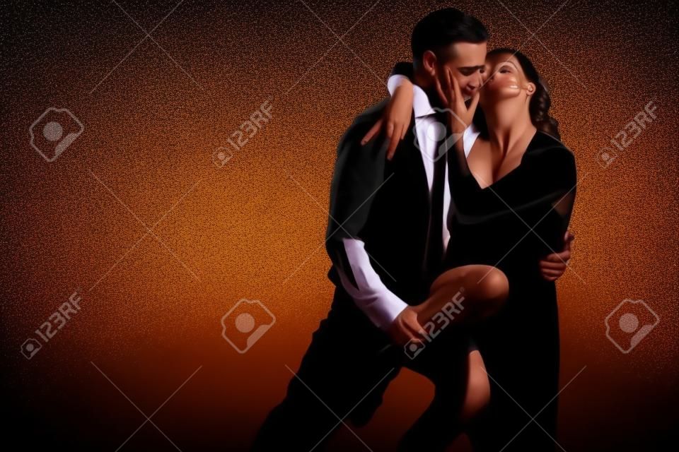 La giovane donna graziosa in vestito nero e l'uomo ballano il tango