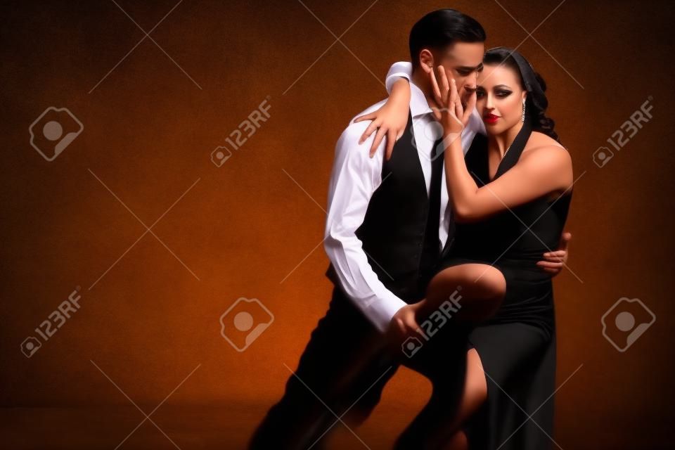 La giovane donna graziosa in vestito nero e l'uomo ballano il tango