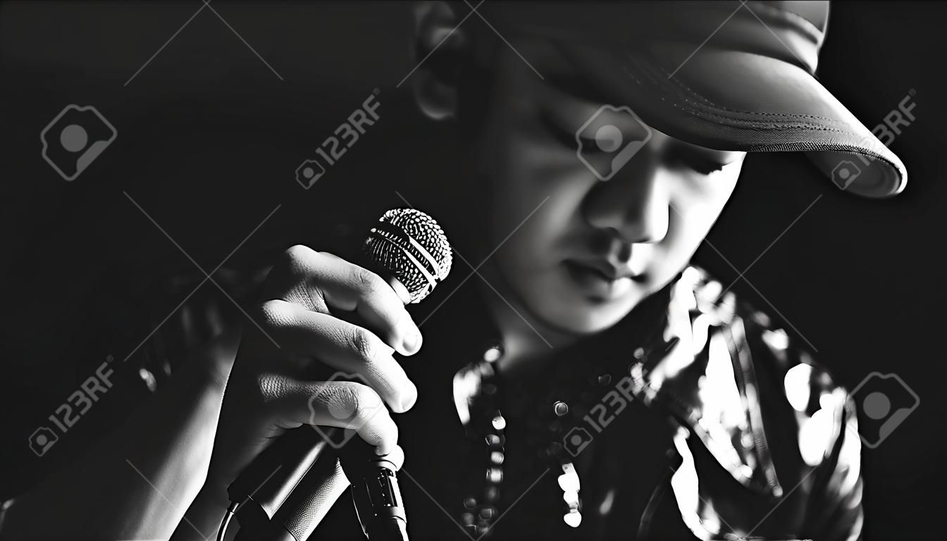 Asian mężczyzna wokalista ręce na mikrofon, czarno-biały