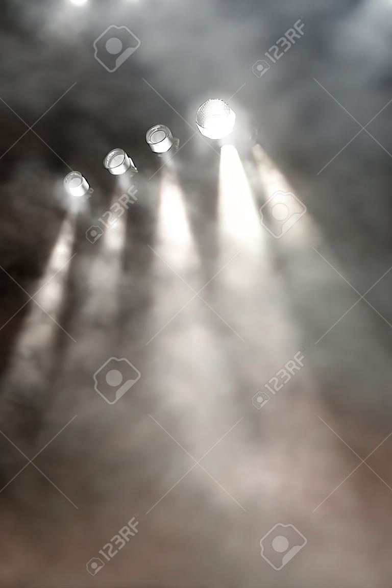 Line of white spotlights shining downwards through smoke and vapour filled air at a concert, disco or entertainment venue