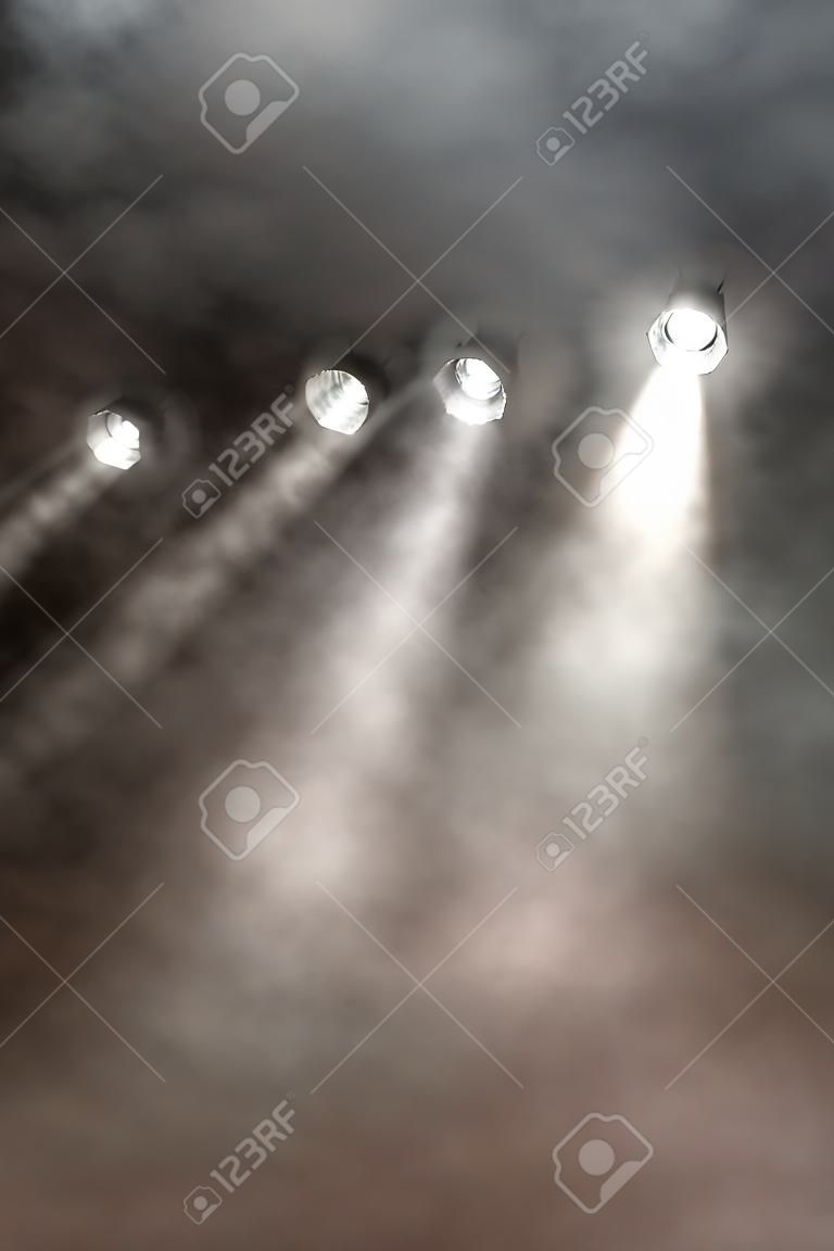 콘서트, 디스코 또는 엔터테인먼트 장소에서 연기와 수증기로 가득 찬 공기를 통해 아래쪽으로 빛나는 흰색 스포트라이트 라인