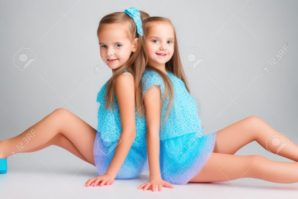Retrato de dos hermanas niñas posando en el estudio. Aislado en blanco.
