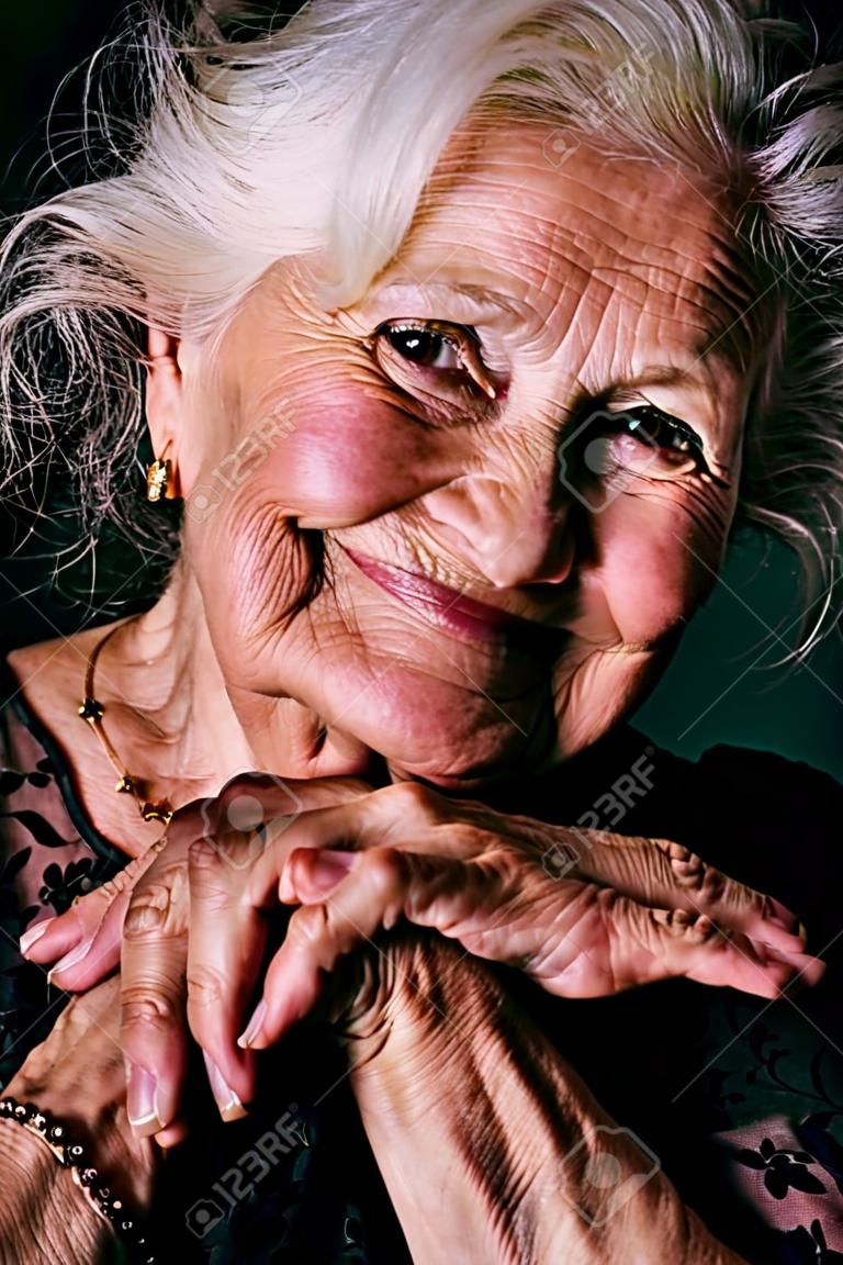 Portrait of a happy senior woman smiling at the camera. Over black background.